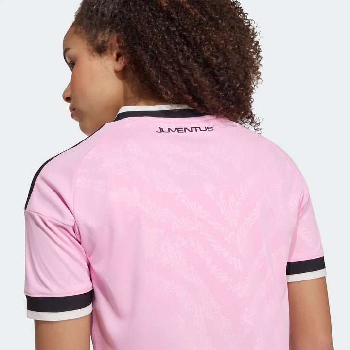 Kids' pink Juventus 26/27 away jersey, featuring the club logo on the back, shown worn from a rear and side perspective.