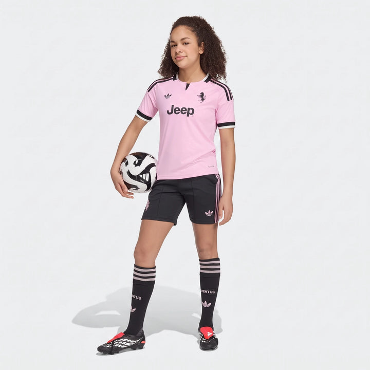 Young girl models a pink and black Juventus 26/27 Away Soccer Jersey for kids, complete with matching shorts, socks, and