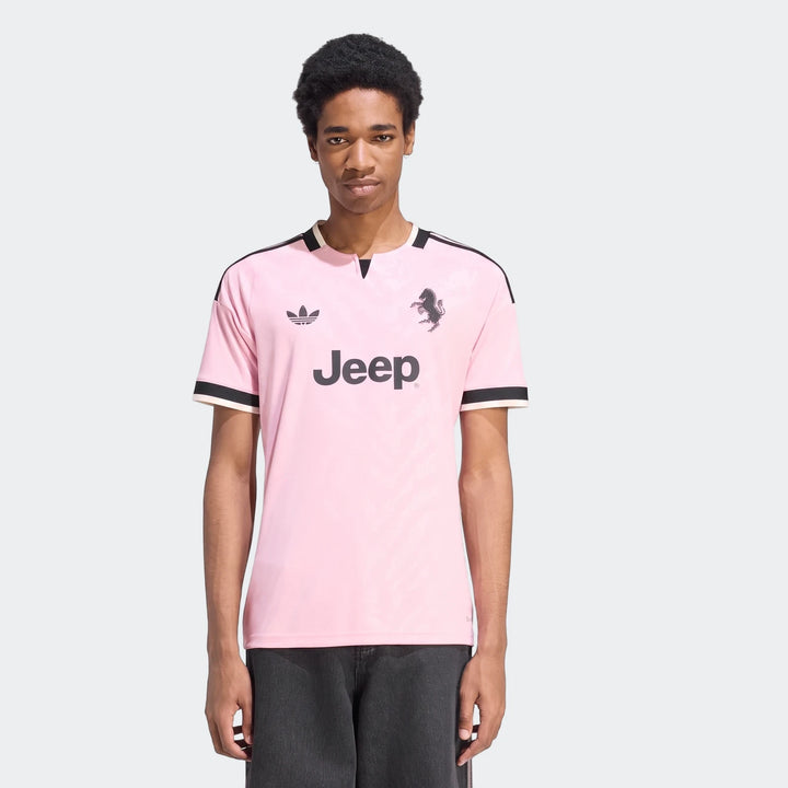 Male model wearing a pink Adidas Juventus 26/27 Away Jersey with Jeep and horse crest logos. Short-sleeve, front view.