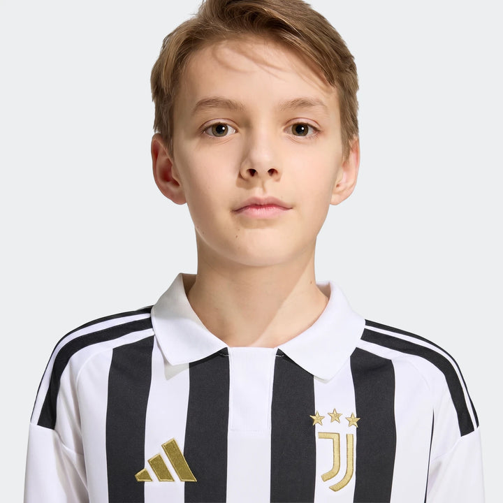 Young boy wearing a Juventus 26/27 Home Jersey for kids, featuring iconic black and white stripes with gold club and Adidas