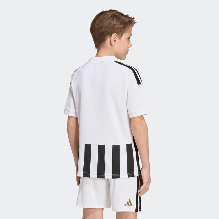 Young boy modeling the Juventus 26/27 Home Jersey and matching shorts in white with black stripes, seen from the back.
