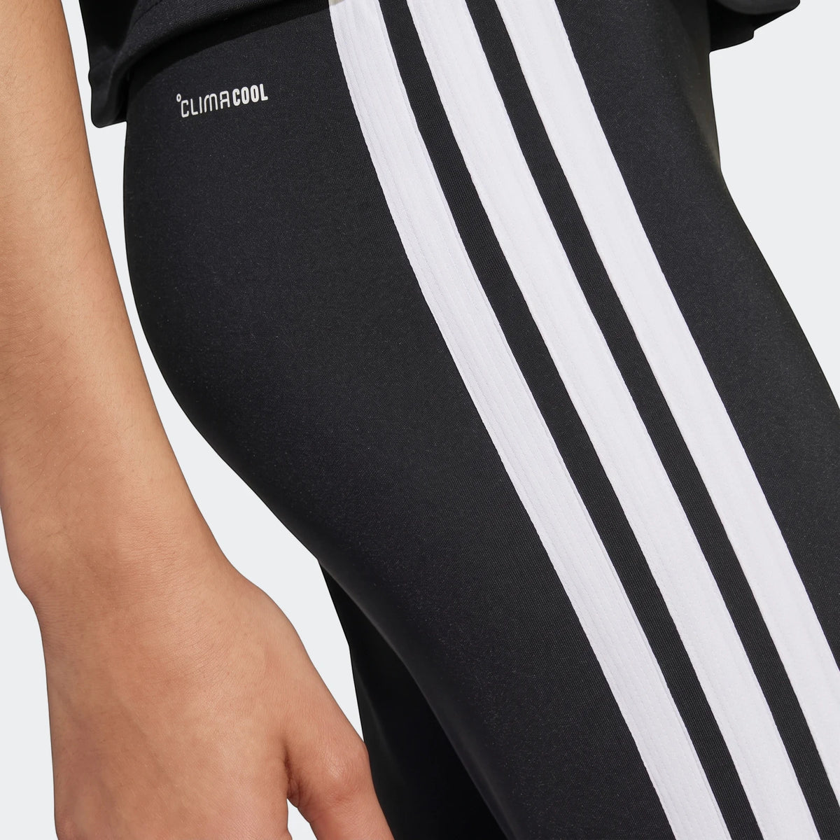 Close-up of Kids' Adidas Train Essentials 3-Stripes Leggings in black, featuring the white ClimaCool logo and three white
