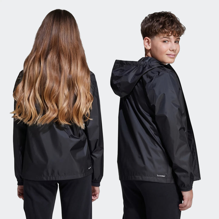 Two kids wearing black rain jackets, with a girl showing the back view and a boy showing a side view.