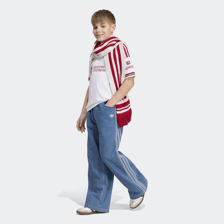 Young boy wearing a Kids Liverpool Fc 26/27 Away Jersey, white with red details, blue striped denim pants, and a red and