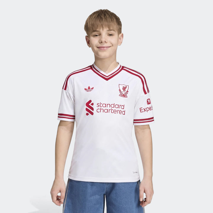 Young boy wearing the Kids Liverpool FC 26/27 Away Jersey, featuring white fabric with red trim, club crest, and sponsor