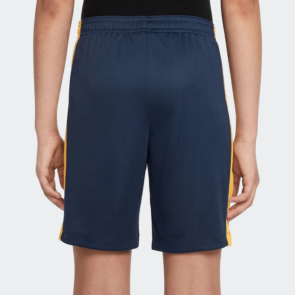 Kids' Nike Dri-FIT Academy 23 blue shorts with yellow side stripes, worn from a back view, ideal for sports activities.