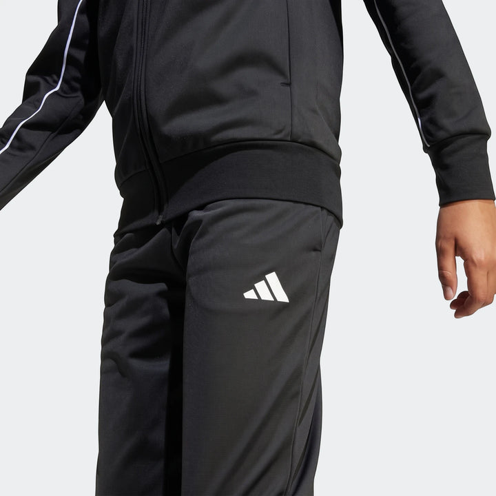 Close-up of a black Kids Tricot Colour Pop Track Suit featuring white piping and an Adidas logo on the leg, designed for
