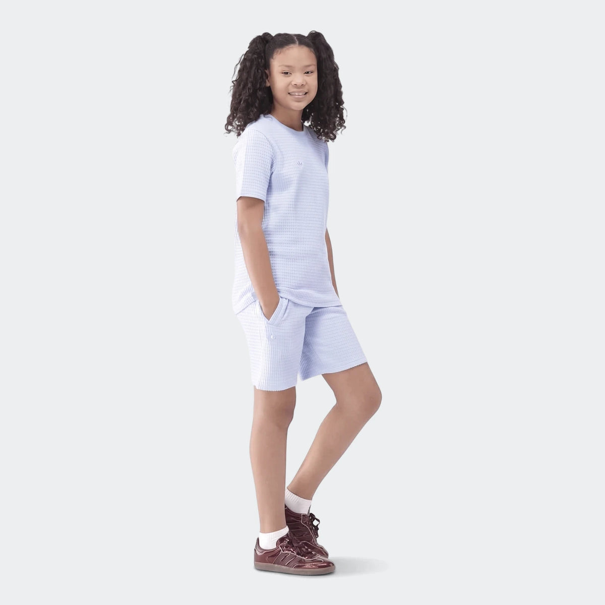 Young girl smiling and posing in a comfortable light blue waffle knit t-shirt and matching shorts set.