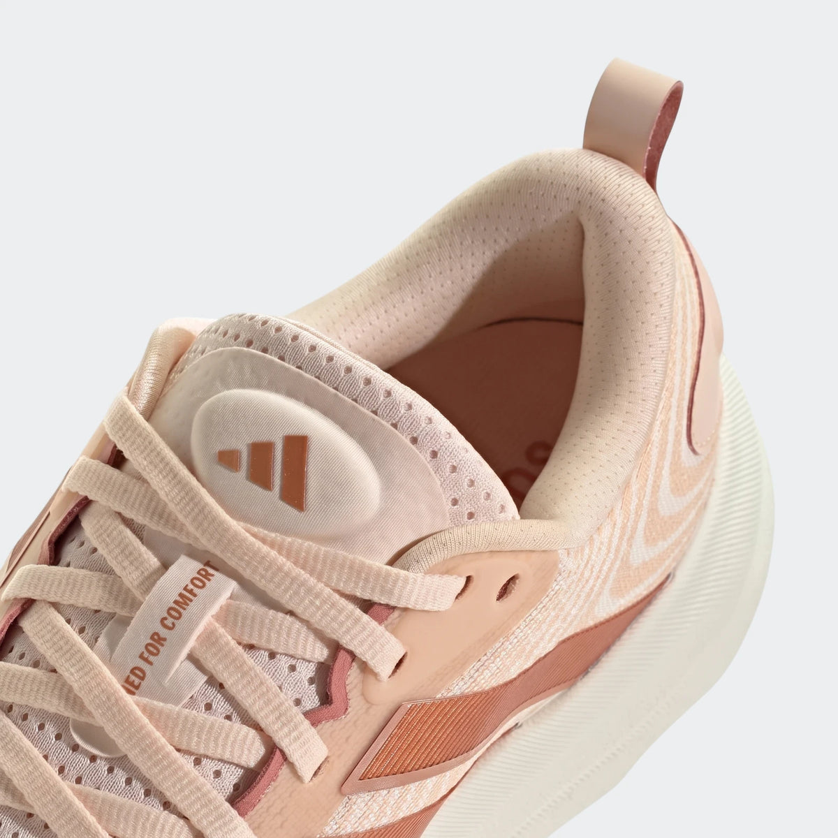 Close-up of a light pink Adidas Supernova Ease 2 running shoe, featuring a mesh upper and peach accents.