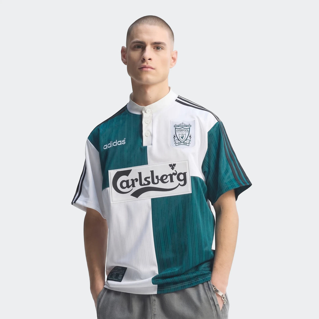 Front view of a male model wearing the white and green Liverpool FC 1995 Away Jersey, featuring the Adidas and Carlsberg