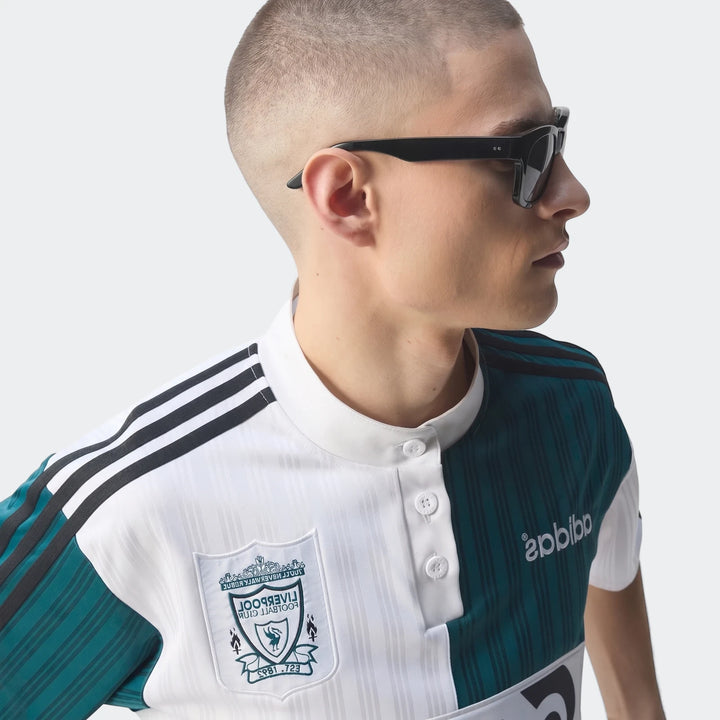 Male model in profile wearing a white and teal green Liverpool FC 1995 Away Jersey and black sunglasses, captured from the