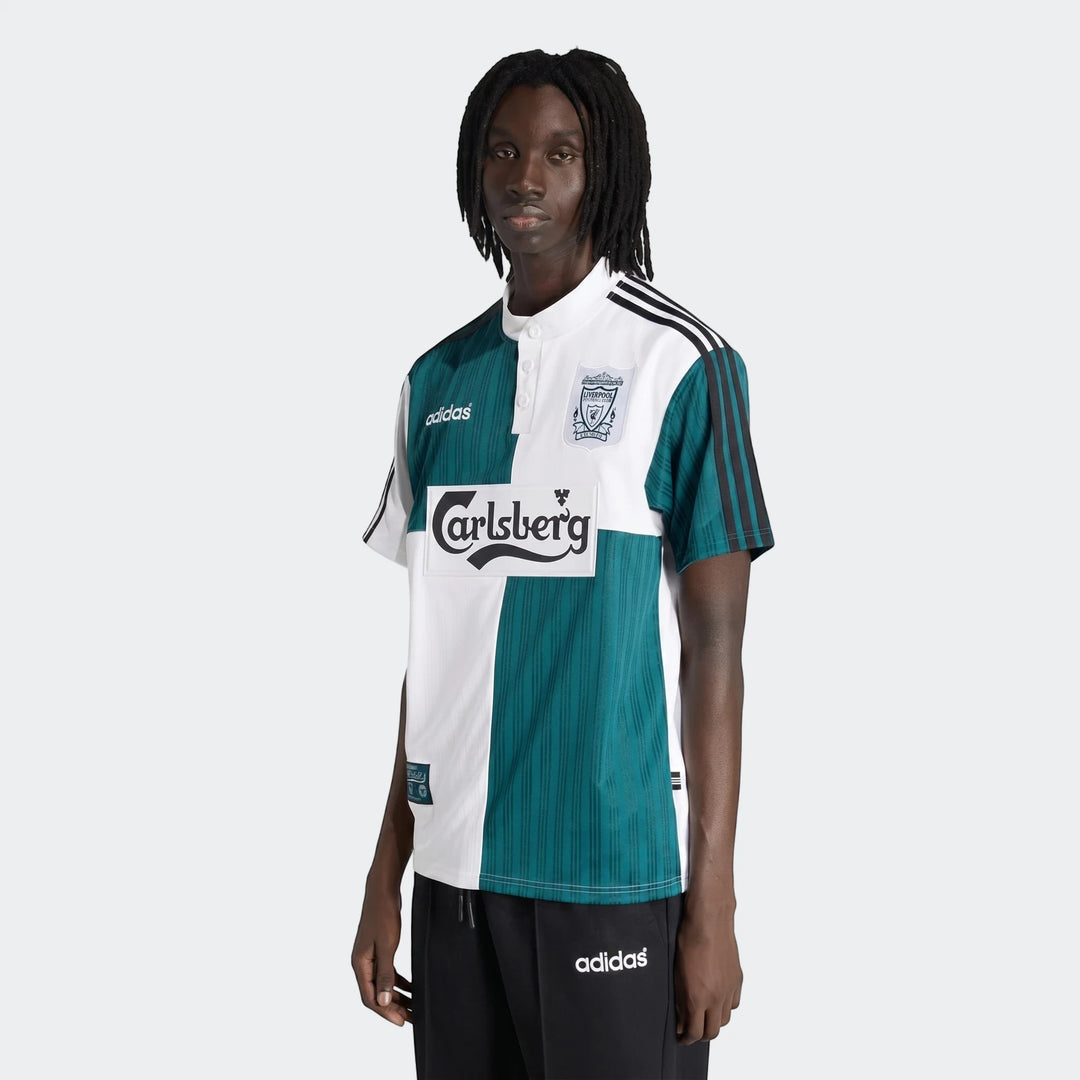 Male model wearing a retro Liverpool Fc 1995 Away Jersey in white and teal with the Carlsberg logo and Adidas stripes.