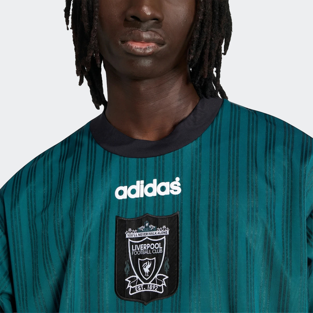 Close-up of a model wearing a dark green striped Liverpool FC 1995 Poly T-Shirt with an Adidas logo and team crest.