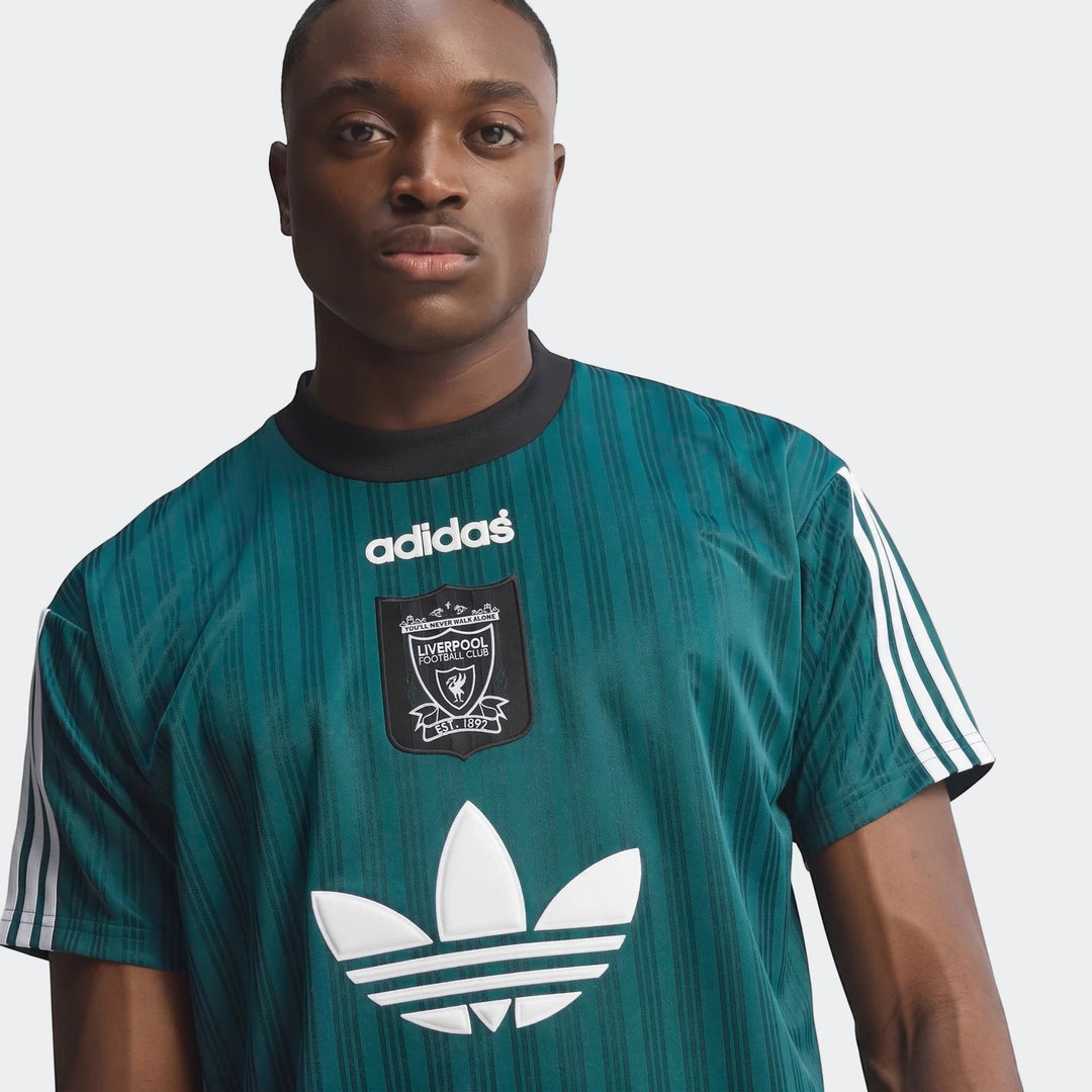 Close-up of a male model wearing a vintage green striped Liverpool FC 1995 Poly T-Shirt with white Adidas branding.
