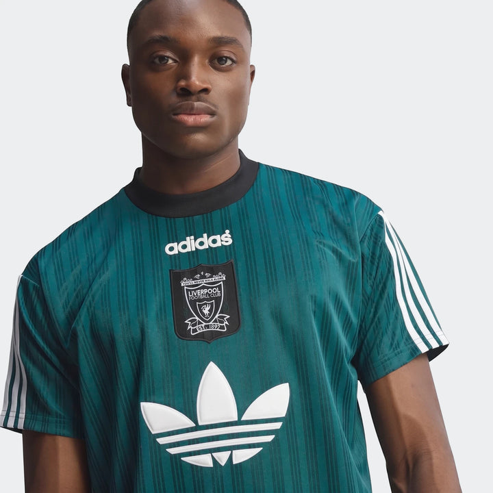 Close-up of a male model wearing a vintage green striped Liverpool FC 1995 Poly T-Shirt with white Adidas branding.