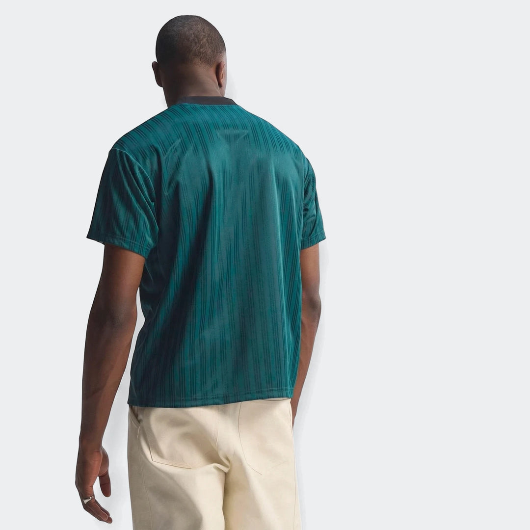A male model from the back wears a dark teal ribbed Liverpool FC 1995 Poly T-Shirt with thin vertical stripes and