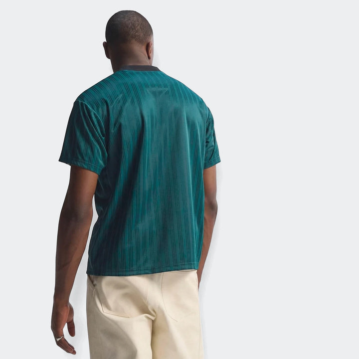 A male model from the back wears a dark teal ribbed Liverpool FC 1995 Poly T-Shirt with thin vertical stripes and