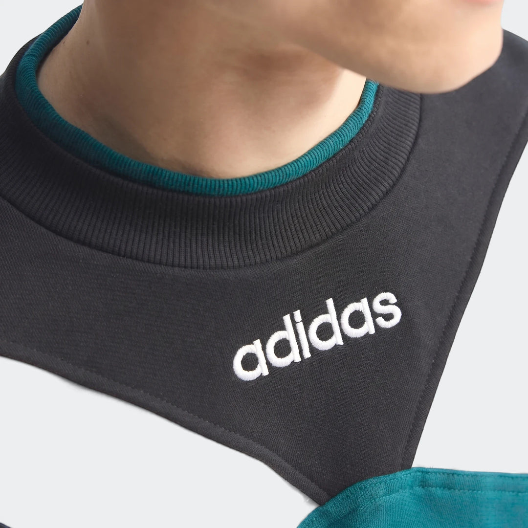 Close-up of a person wearing a vintage Liverpool FC 1995 sweatshirt featuring black, white, and teal color blocks and an