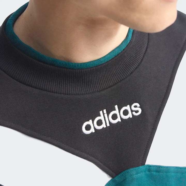 Close-up of a person wearing a vintage Liverpool FC 1995 sweatshirt featuring black, white, and teal color blocks and an