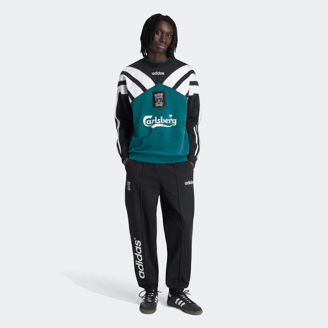 Male model wearing a vintage Liverpool FC 1995 sweatshirt in black, white, and teal, paired with black adidas track pants