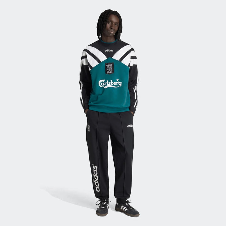 Male model wearing a vintage Liverpool FC 1995 sweatshirt in black, white, and teal, paired with black adidas track pants