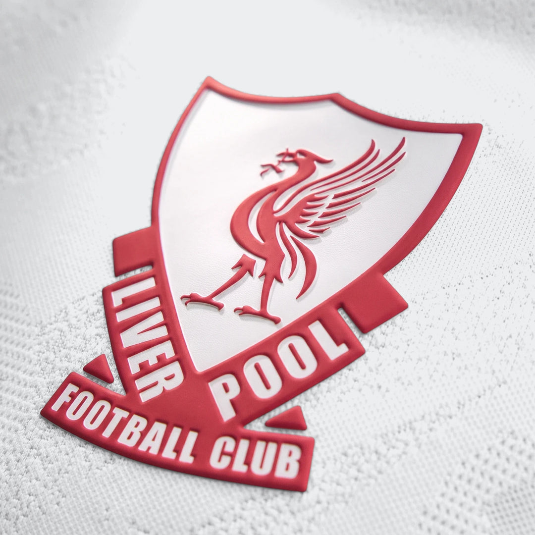 Close-up of the embossed red and white Liverpool FC crest on a white 26/27 Away Authentic Longsleeve Jersey, showcasing the