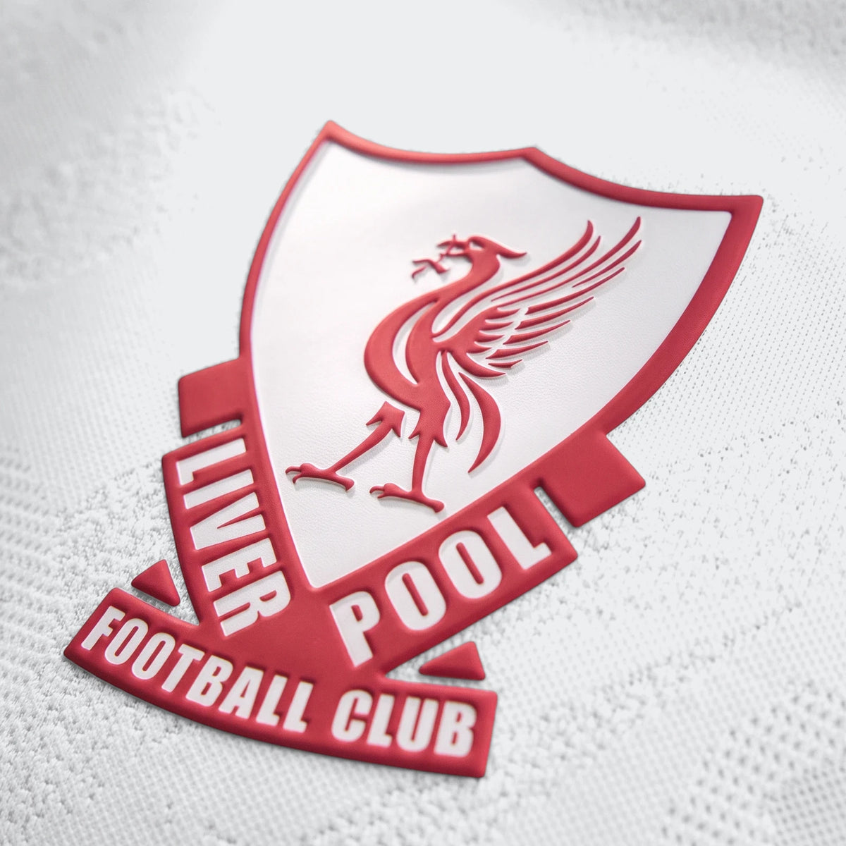 Close-up of the embossed red and white Liverpool FC crest on a white 26/27 Away Authentic Longsleeve Jersey, showcasing the
