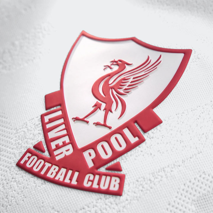 Close-up of the embossed red and white Liverpool FC crest on a white 26/27 Away Authentic Longsleeve Jersey, showcasing the