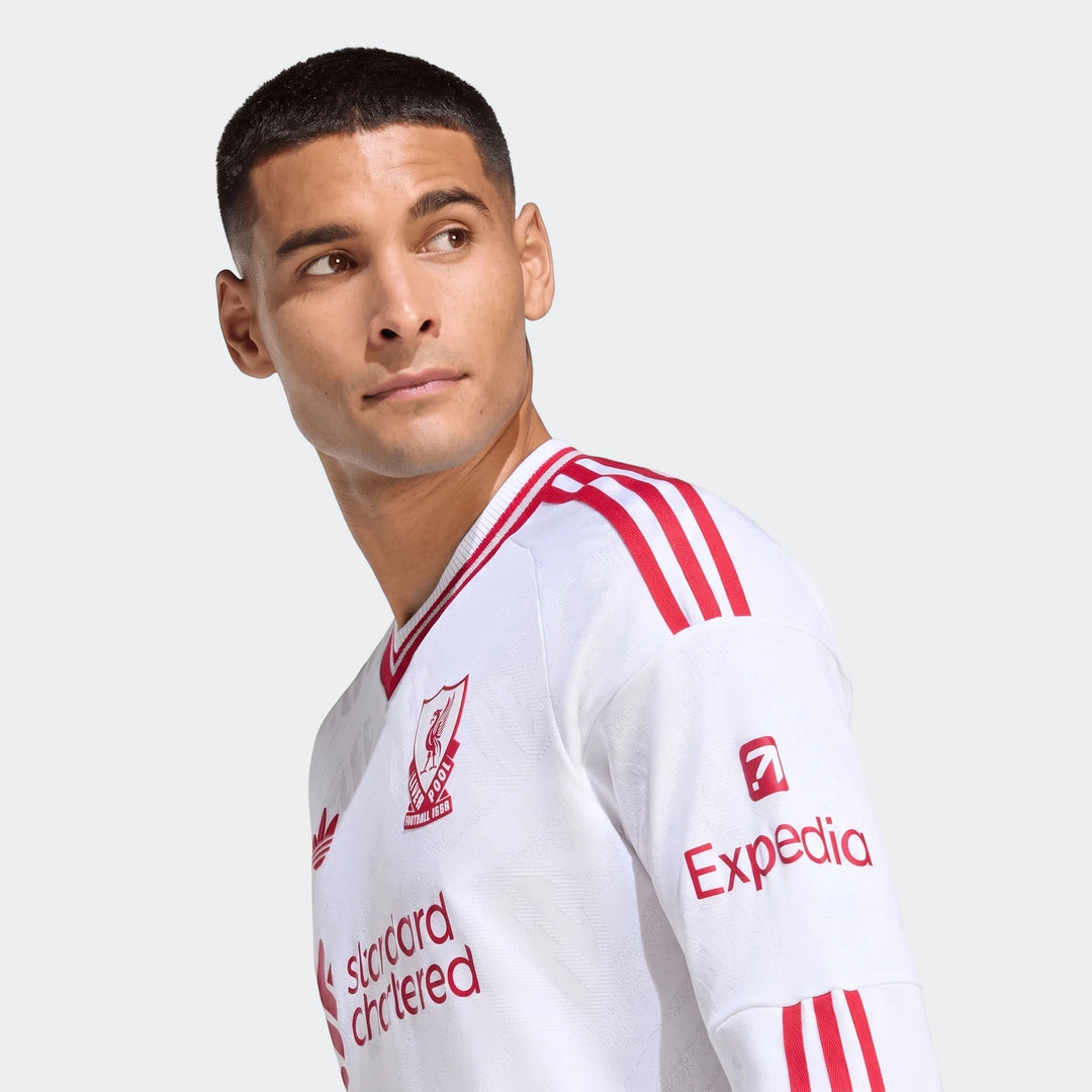 Close-up of a male model wearing the white Liverpool FC 26/27 Away Authentic Longsleeve Jersey, featuring red stripes and