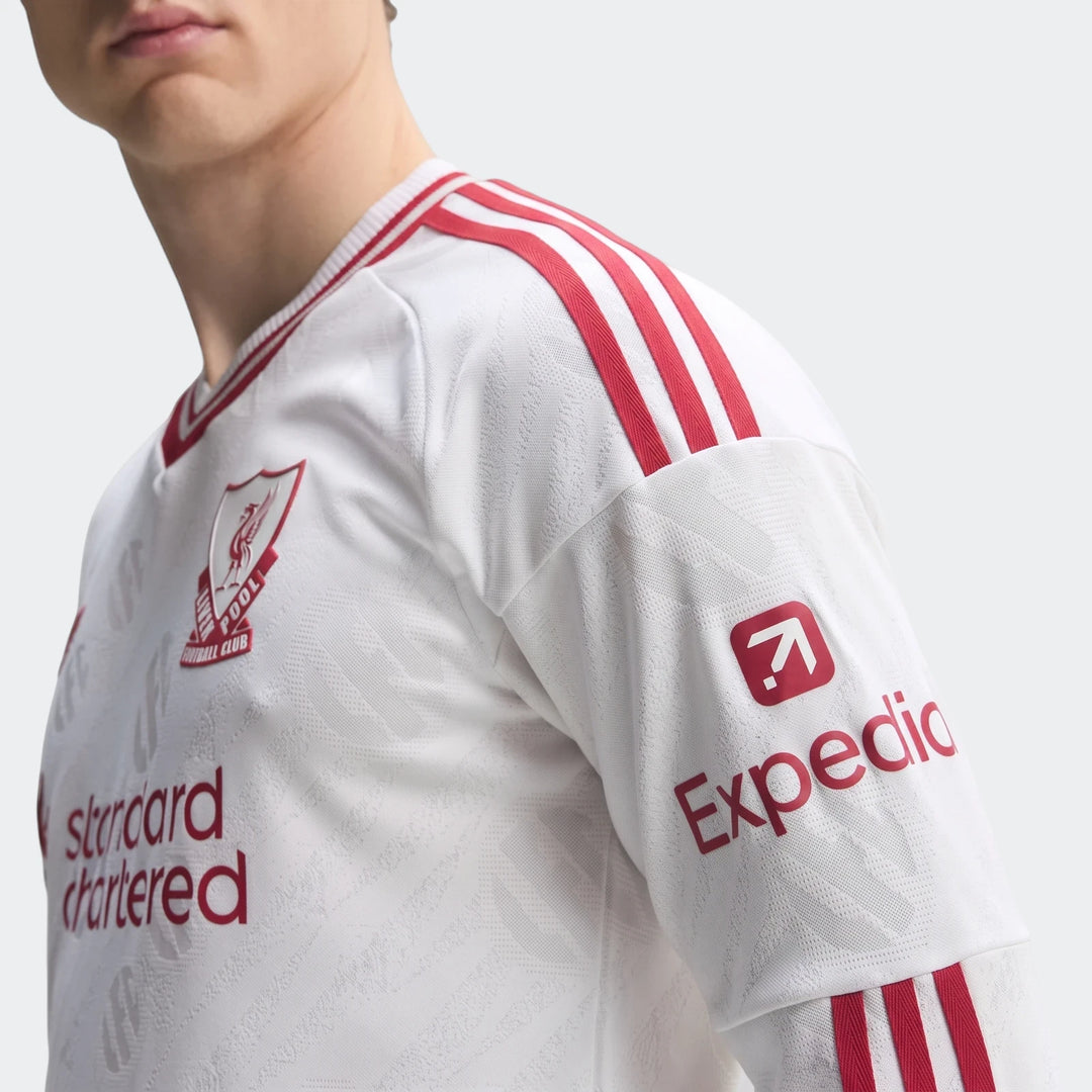 Close-up of a man wearing a white Liverpool FC 26/27 Away Authentic Longsleeve Jersey with red stripes and sponsor logos.