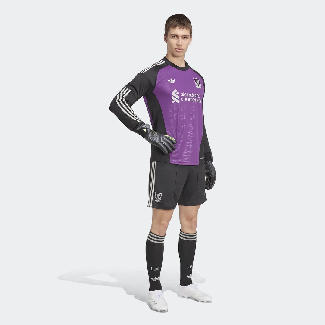 Young male model wearing the Liverpool FC 26/27 Away Goalkeeper Jersey in purple and black with matching shorts, socks, and