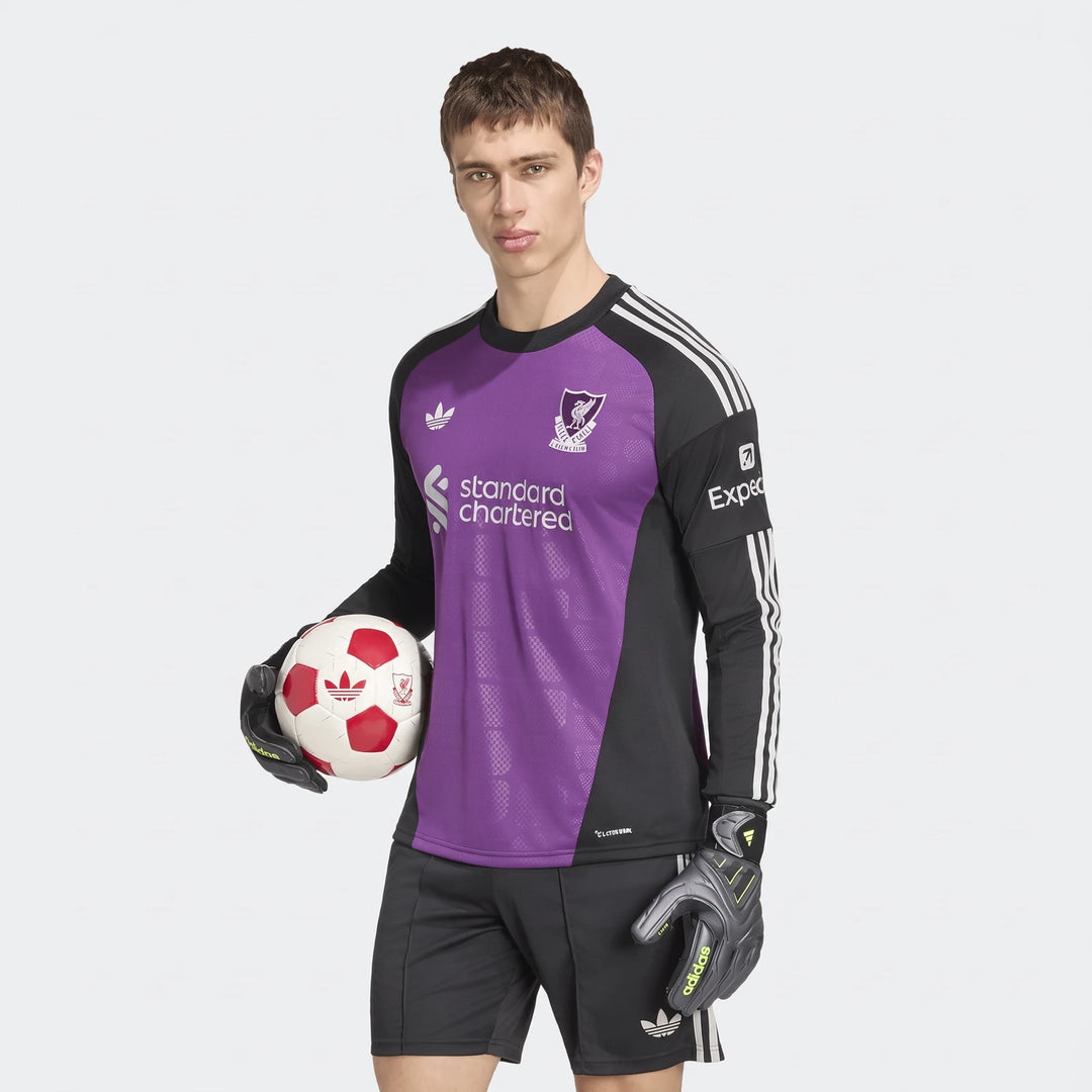 Male model wearing a purple and black Liverpool FC 26/27 Away Goalkeeper Jersey, matching shorts, and gloves, holding a