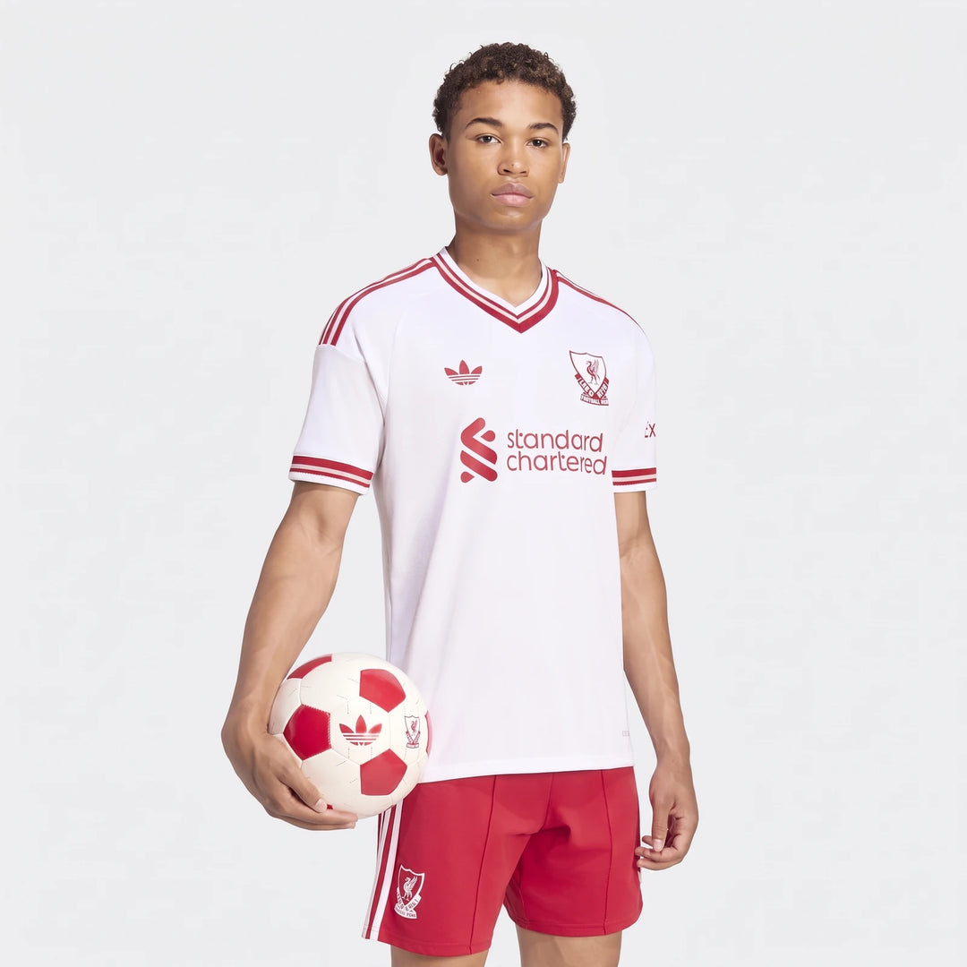 Male model wearing an authentic Liverpool FC 26/27 Away Jersey in white and red, holding a soccer ball.