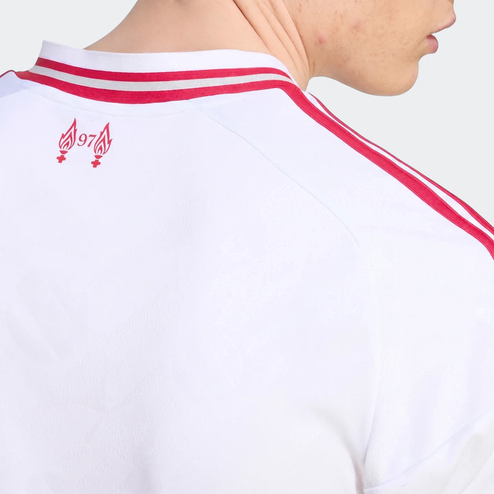 Close-up of the back of a white Liverpool FC 26/27 away jersey with red shoulder stripes and a red '97' flame logo worn by a