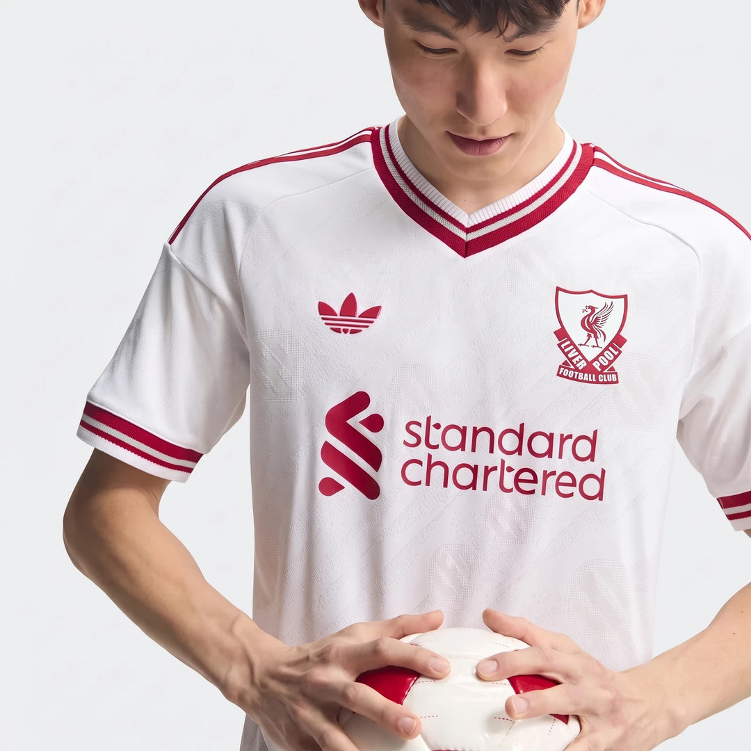 Authentic Liverpool FC 26/27 Away Jersey in white and red, worn by a male model holding a football.