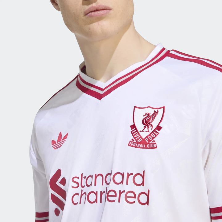 Liverpool Fc 26/27 Away Jersey, white with red trim and logos, worn by a person, captured in a close-up studio shot.