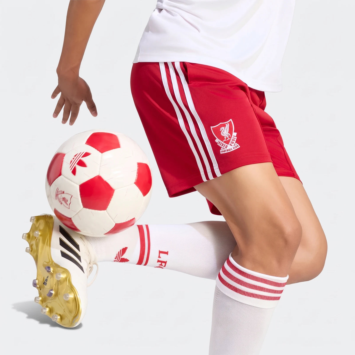 Red Adidas Liverpool FC 26/27 Away Shorts with white stripes, worn by a soccer player juggling a red and white ball.