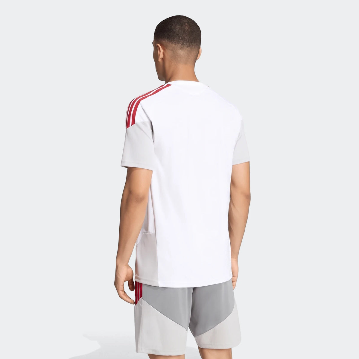 Man from back wearing white Liverpool FC 26/27 Cup Tiro training jersey with red stripes and grey shorts.