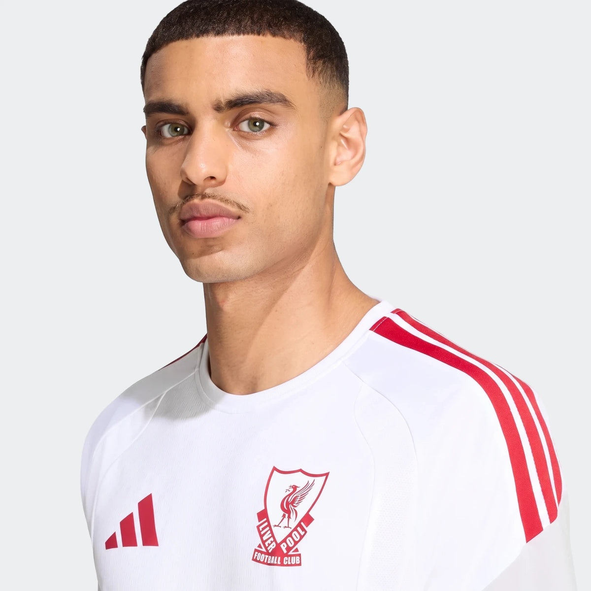 A male model wears a white Liverpool FC 26/27 Cup Tiro Training Jersey, featuring red Adidas stripes on the shoulders and