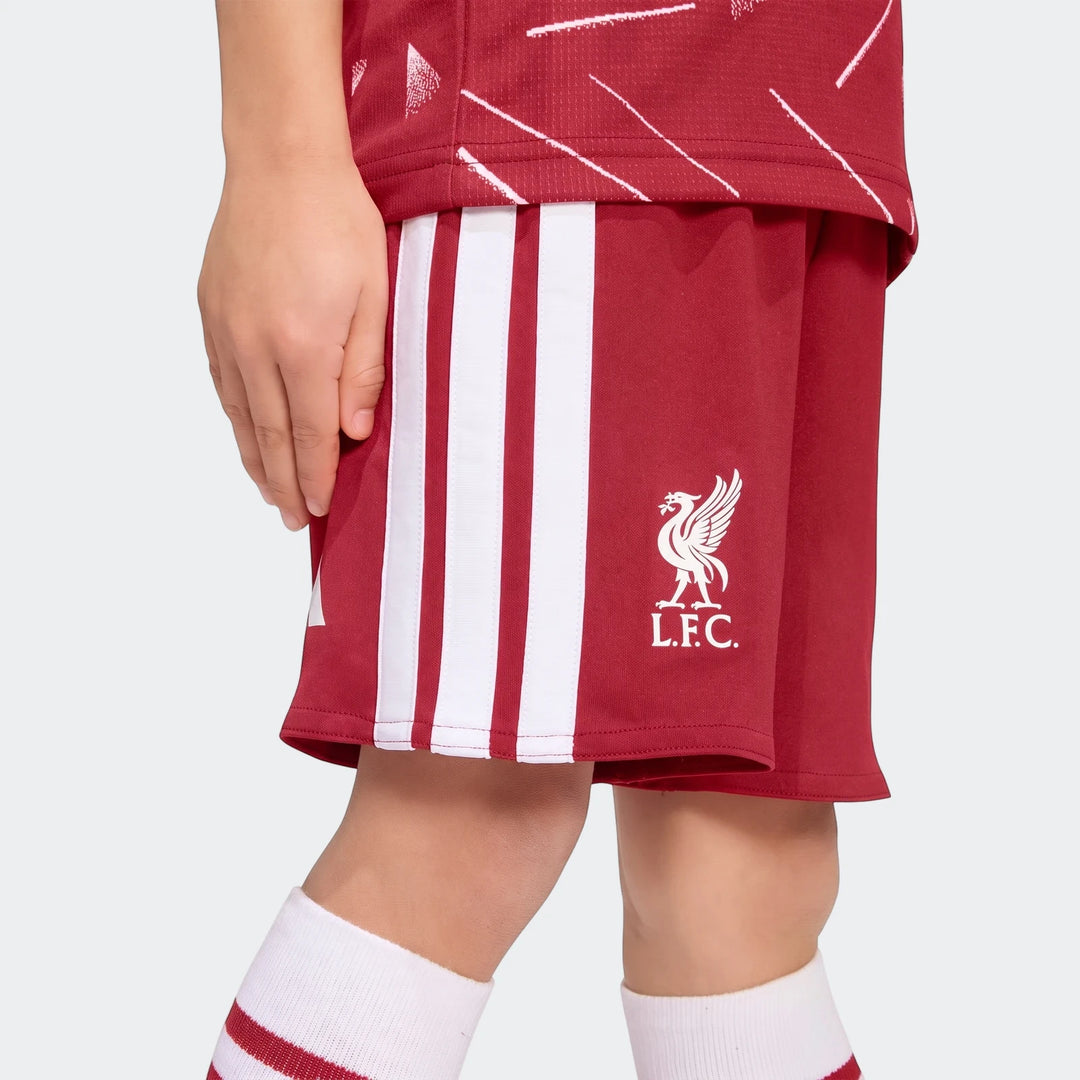 Close-up of a child wearing a red and white Liverpool FC 26/27 Home Kids Set, featuring white stripes and the LFC crest on