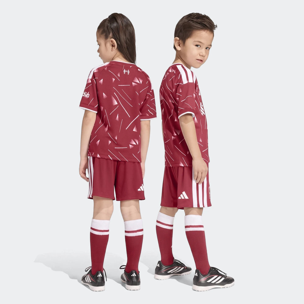 Two children wearing red and white Liverpool FC 26/27 home kids soccer sets, including jerseys, shorts, and socks, posing on