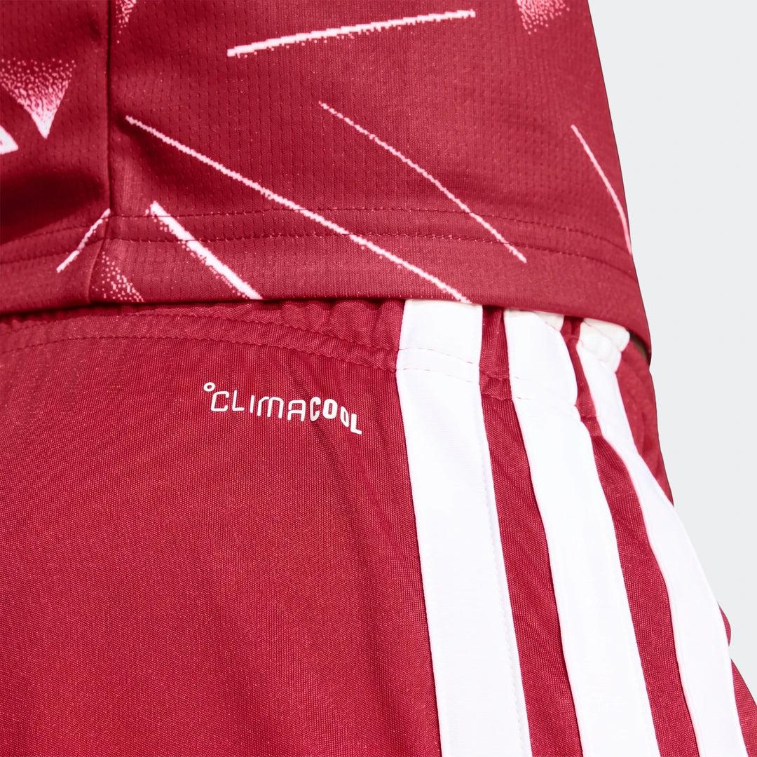 Close-up of Liverpool FC 26/27 home shorts in red with white stripes and a 'CLIMACOOL' logo, shown with matching jersey.