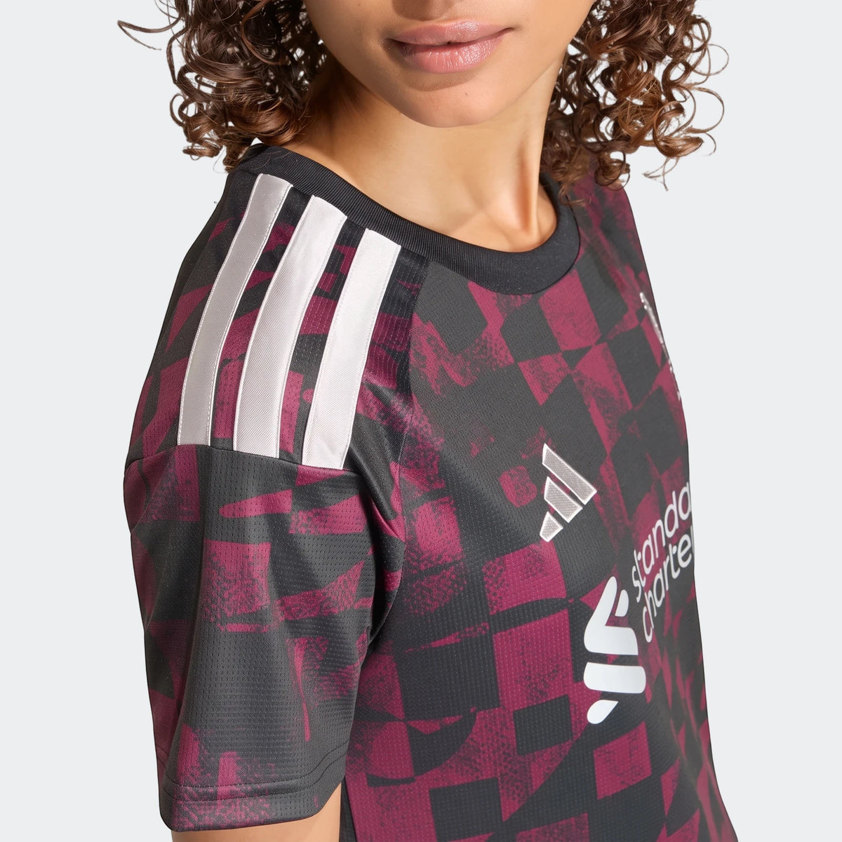 Close-up of a woman wearing a Liverpool FC 26/27 Third Jersey in dark gray and burgundy, with white Adidas stripes.
