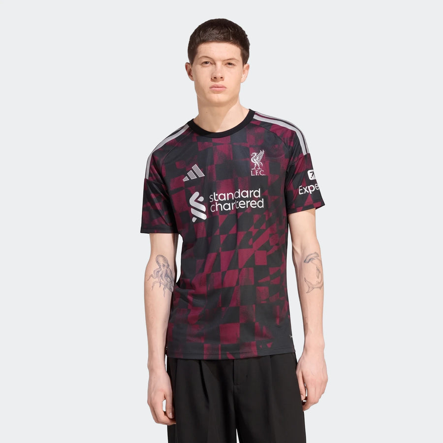 Male model wearing a Liverpool FC 26/27 Third Jersey with a dark gray and maroon checkered pattern and short sleeves.