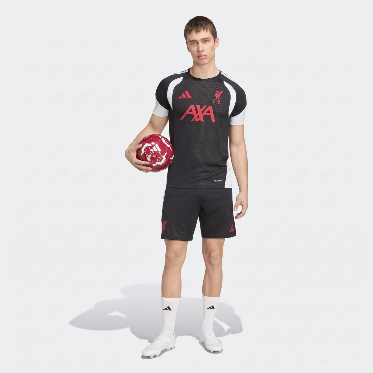 Male model in black Liverpool FC 26/27 Tiro Training Jersey and shorts, holding a football, full body view.