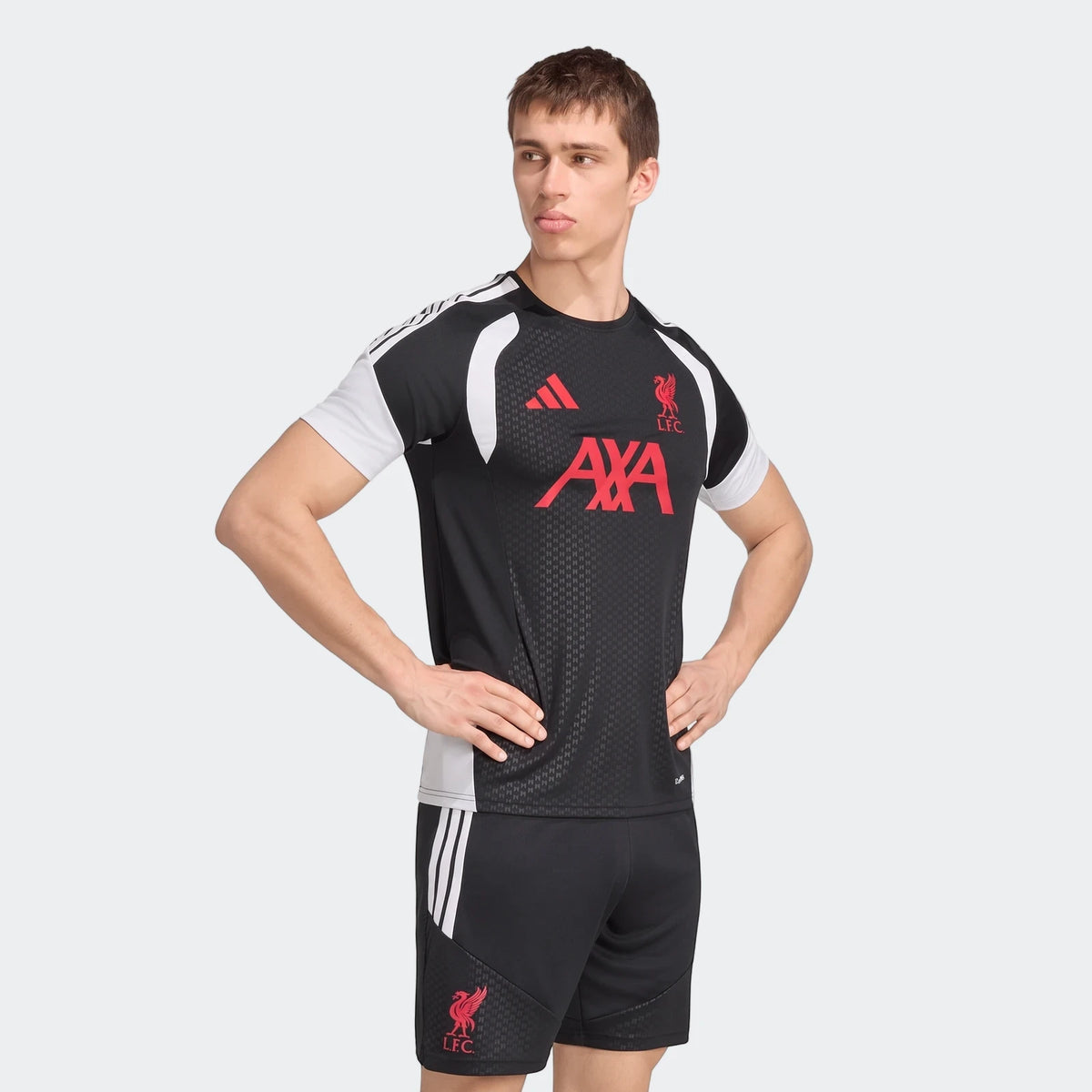 Male model wearing a black, white, and red Liverpool FC 26/27 Tiro Training Jersey and matching shorts in a standing pose.