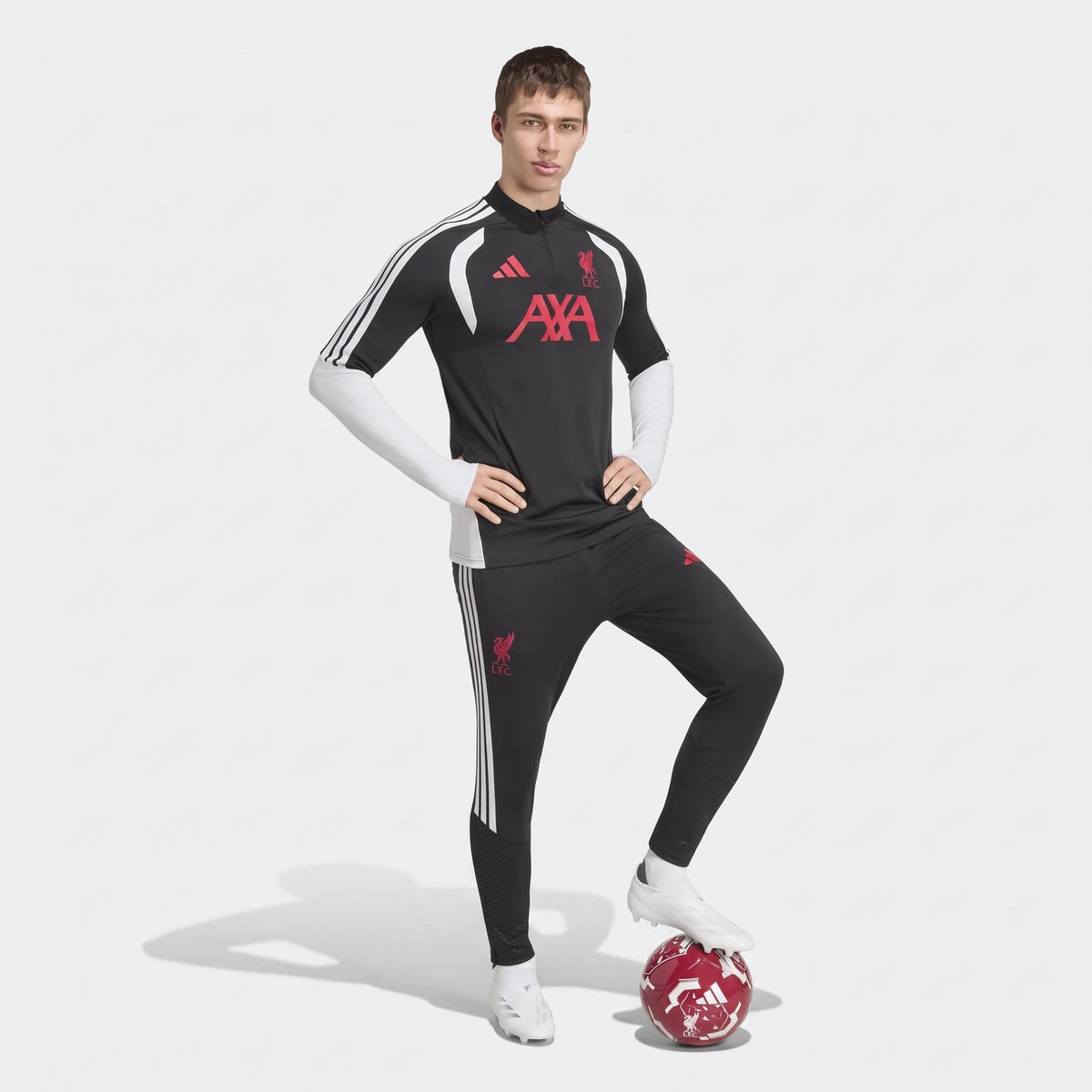 Male model wearing a black Liverpool Fc 26/27 Tiro Training Top and matching black pants, with white cleats and a red soccer