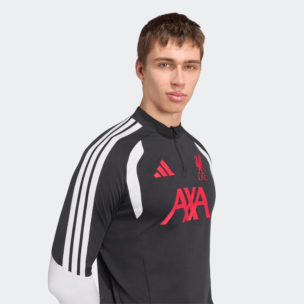 Male model wearing a dark gray Liverpool FC 26/27 Tiro Training Top with red logos and white Adidas stripes.