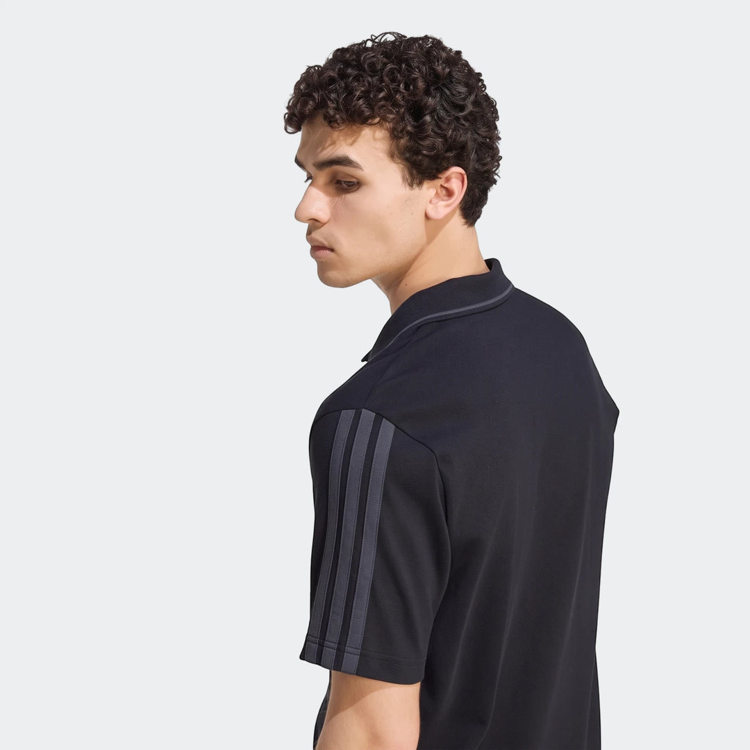 Male model wearing a black Liverpool FC DNA polo shirt with gray shoulder stripes, viewed in profile.