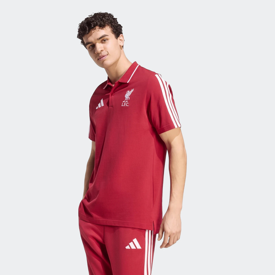 Male model wearing a red Adidas Liverpool FC DNA Polo Shirt and matching sweatpants, posed with a hand in his pocket.